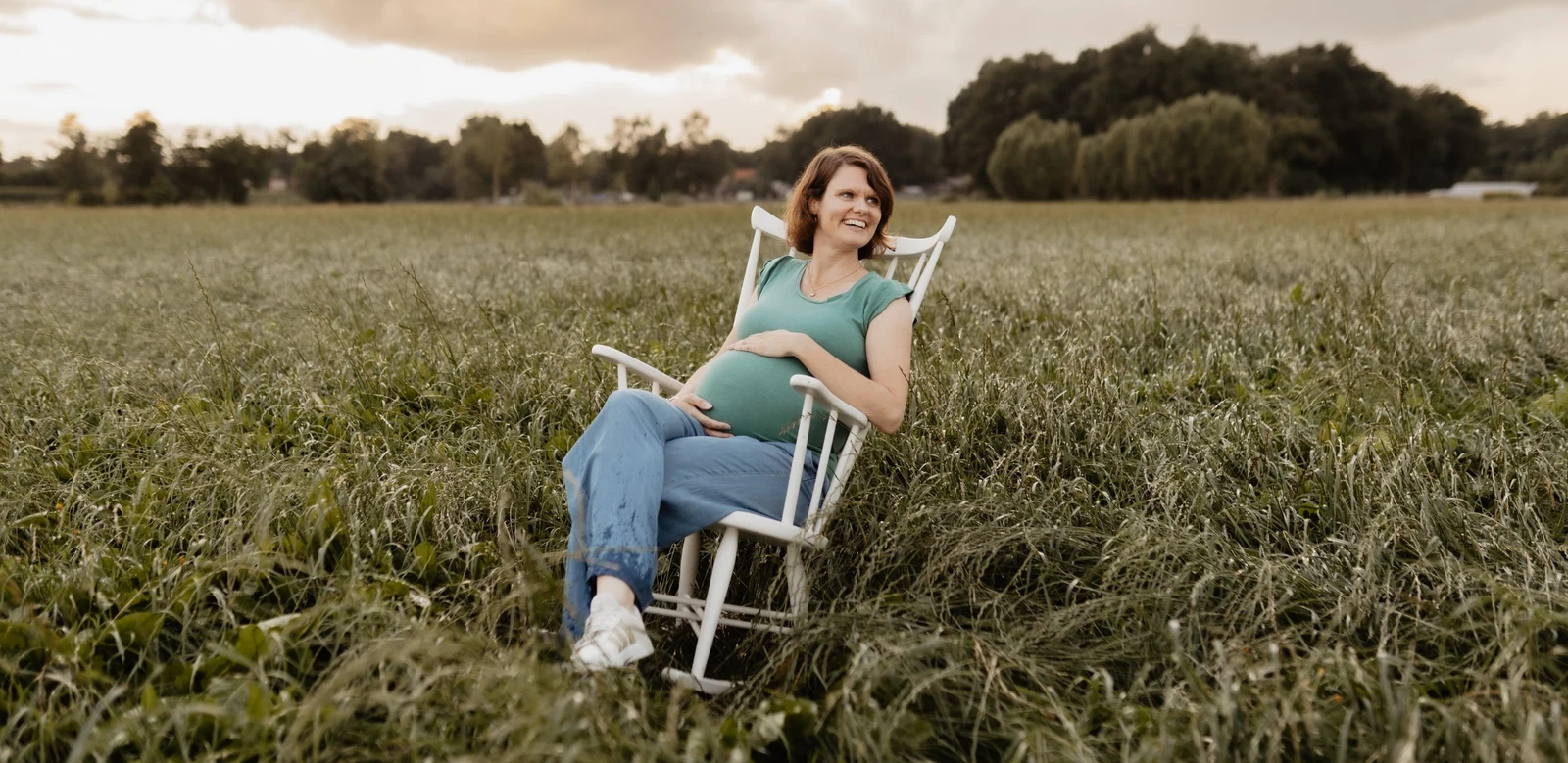 Chantal Kamphorst, zwanger, in een schommelstoel in het hoge gras